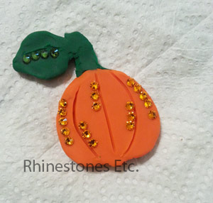Adding green and orange rhinestones to pumpkin pin