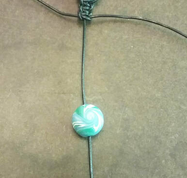 Sliding a bead on the center cord in macrame bracelet making
